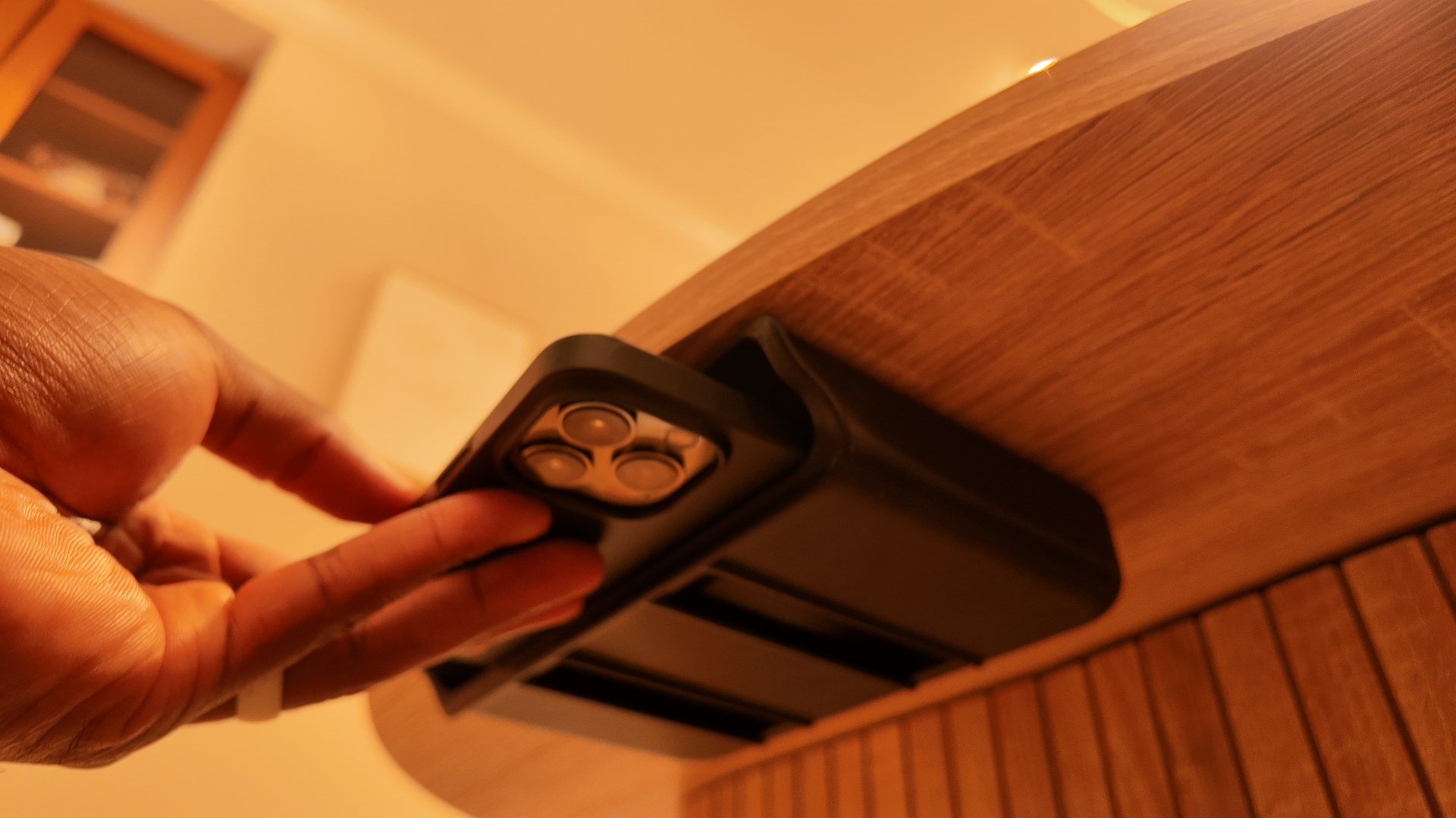 The Good Box mounted discreetly under a wooden desk, cradling a smartphone